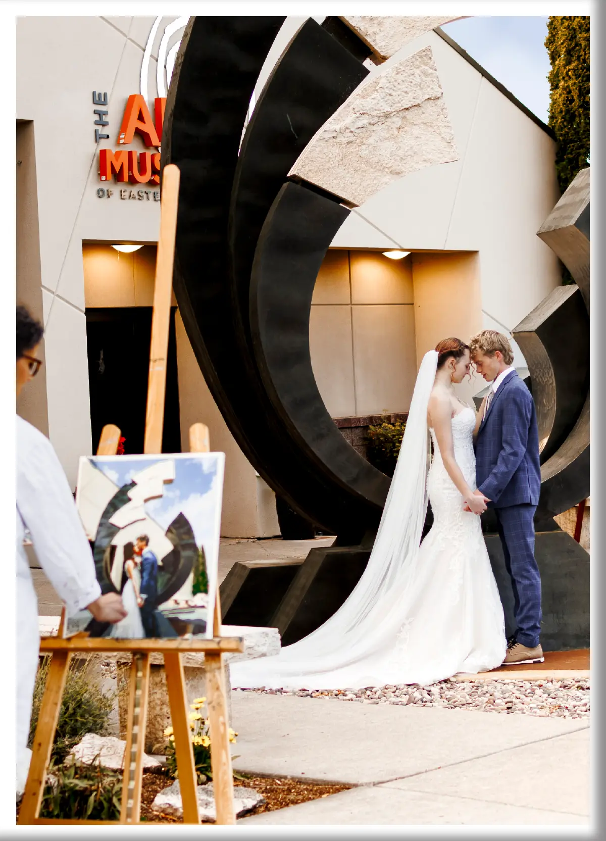 A bride and groom posing for a portrait in front of a large modern metal sculpture at The Art Museum of Eastern Idaho in Idaho Falls.