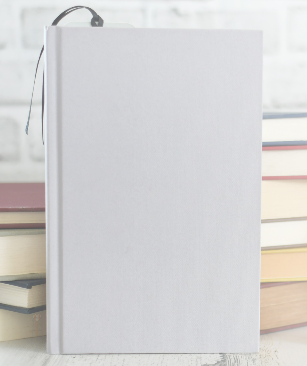 close up of blank book over with stack of books in the background