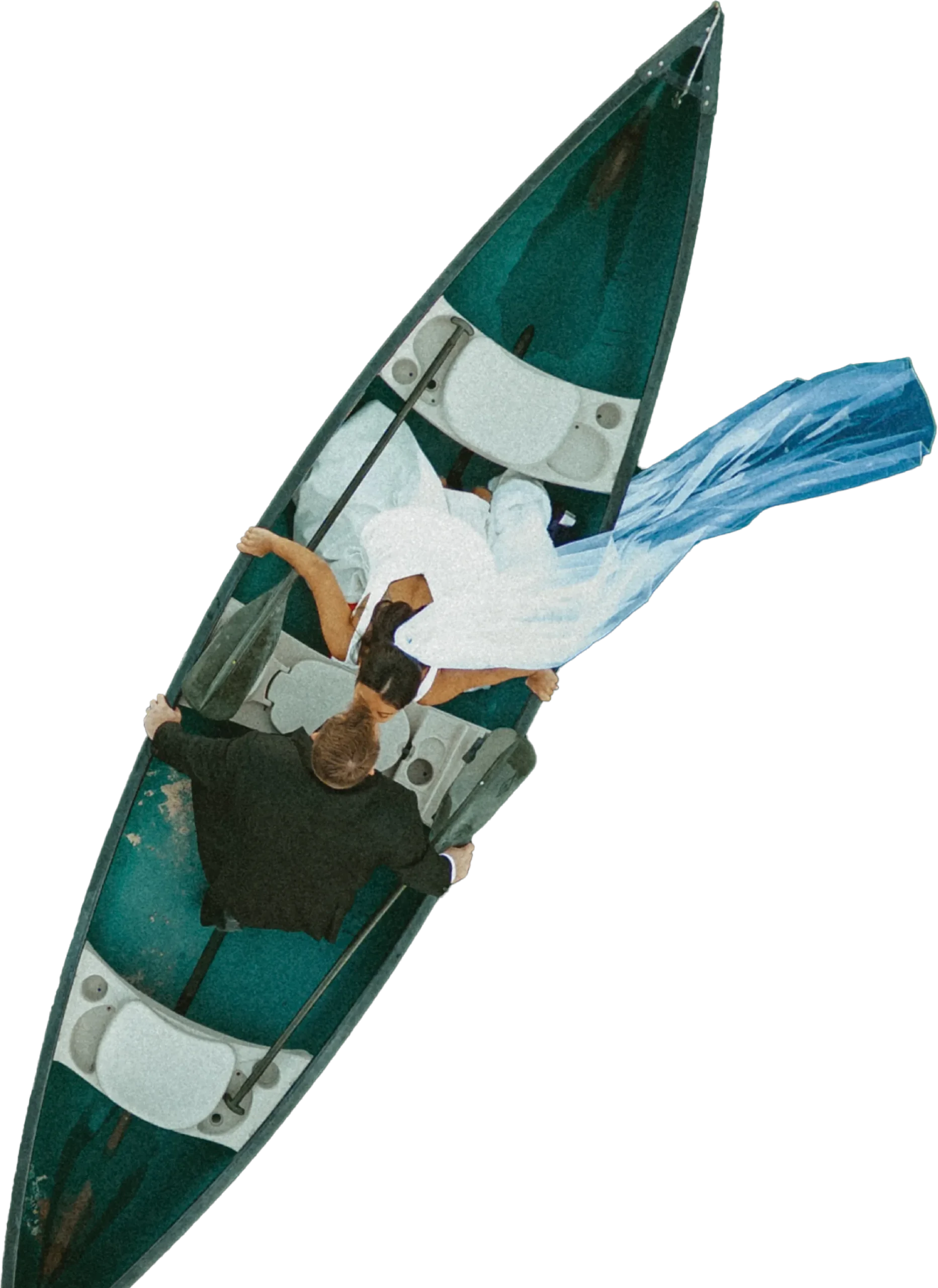 High-angle bird's-eye view of a bride and groom kissing in a green canoe.