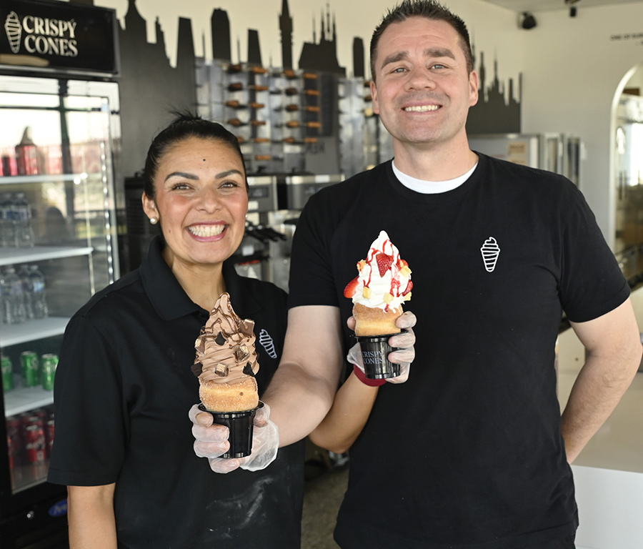 Karla and Moroni Corral smile while holding chocolate and strawberry soft-serve pastry cones.