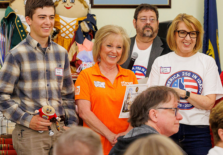 A group of smiling people gathered indoors, with one woman holding a certificate.