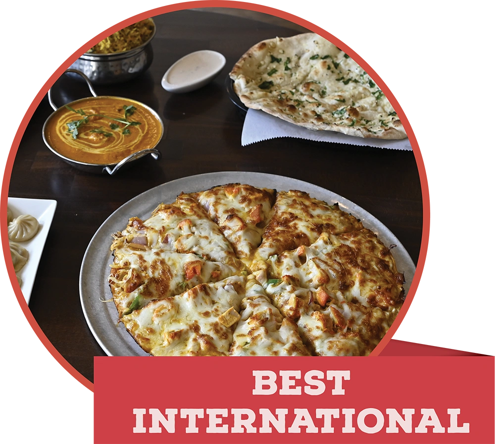 An Indian feast with naan bread, curry, and a chicken tikka pizza, featuring a red banner reading "BEST INTERNATIONAL."