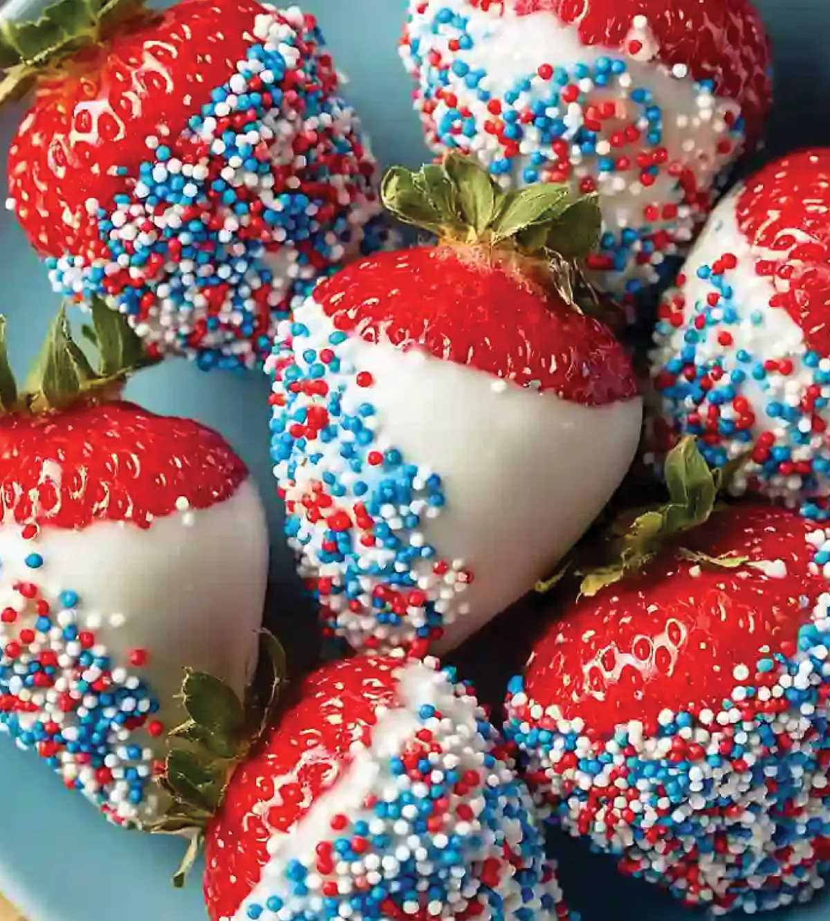 Close-up of fresh strawberries dipped in white chocolate and red, white, and blue sprinkles.