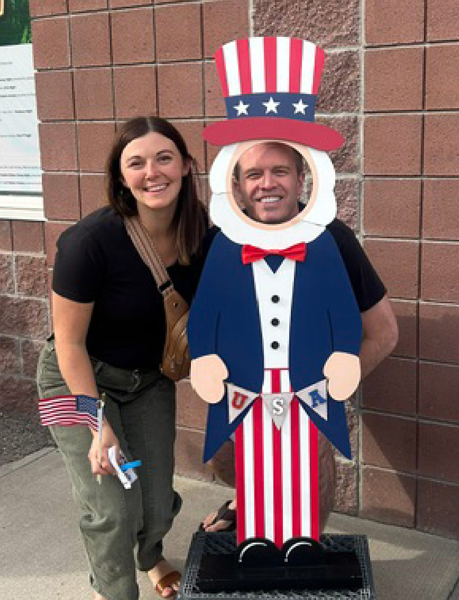 A woman poses next to a man sticking his head through an Uncle Sam cutout.