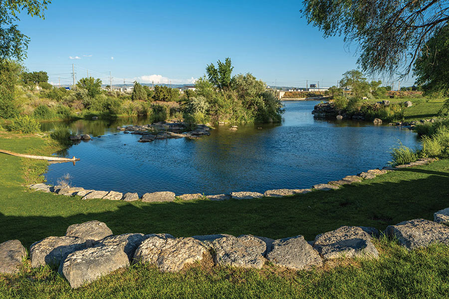 A scenic view of a quiet pond lined with rocks and green grass.