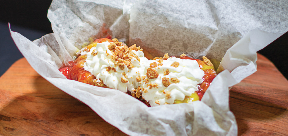 Fruit dessert topped with whipped cream and crushed cookie crumbs served in parchment paper.