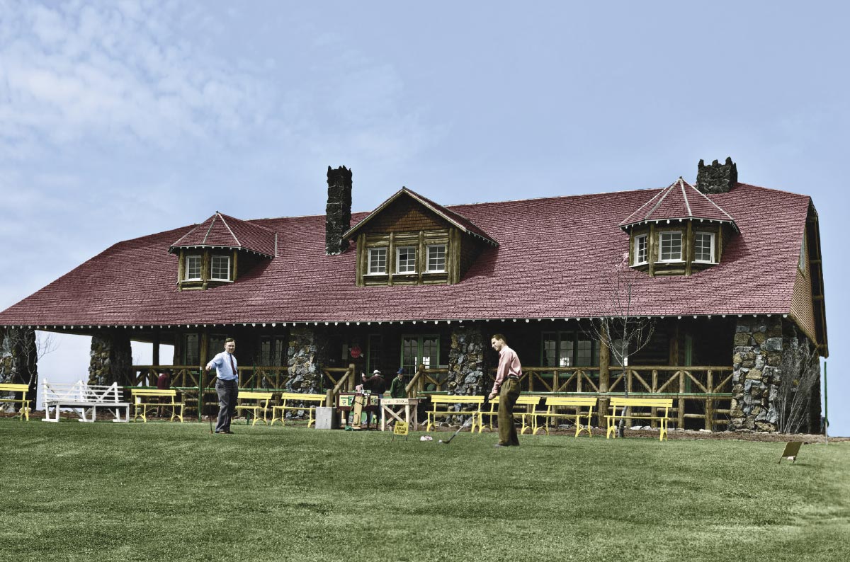 Historical photo of two men golfing on a green in front of a rustic log and stone clubhouse.
